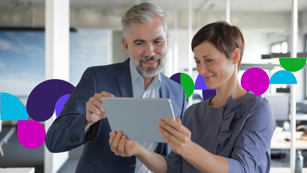 Two colleagues reviewing information on a tablet in an office.