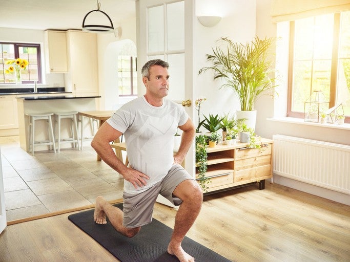 Man doing a lunge exercise on a yoga mat at home.