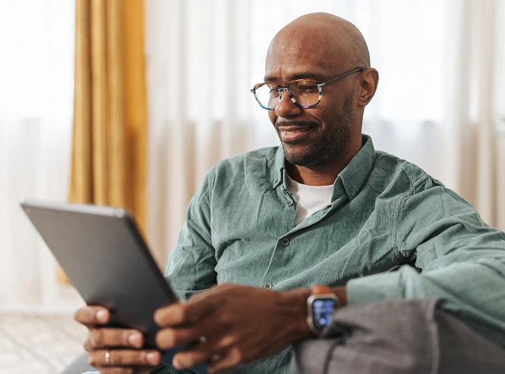 Smiling man sitting at home using a laptop during a virtual healthcare appointment.