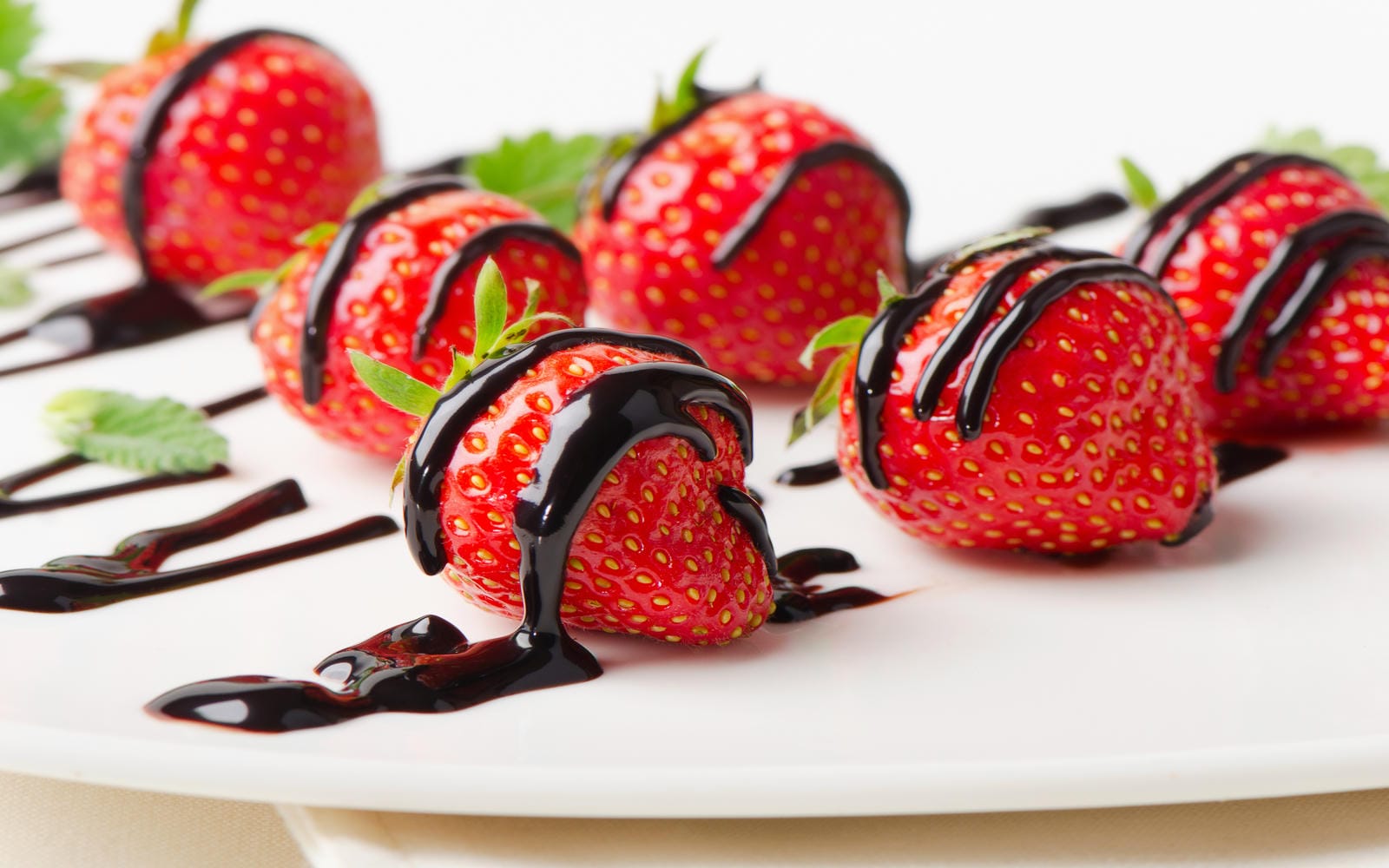 Fresh strawberries dipped in chocolate sauce on white plate. Selective focus