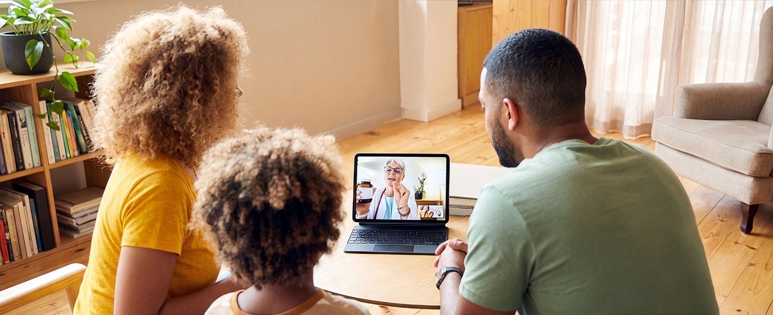 Family gathered around a laptop at home, participating in a video call.