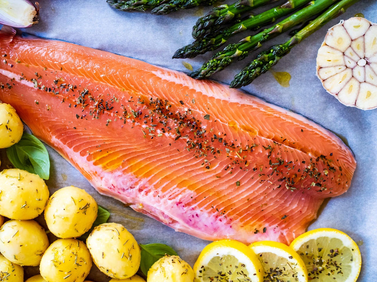 Salmon fillet on a sheet-pan with potatoes, garlic and asparagus.