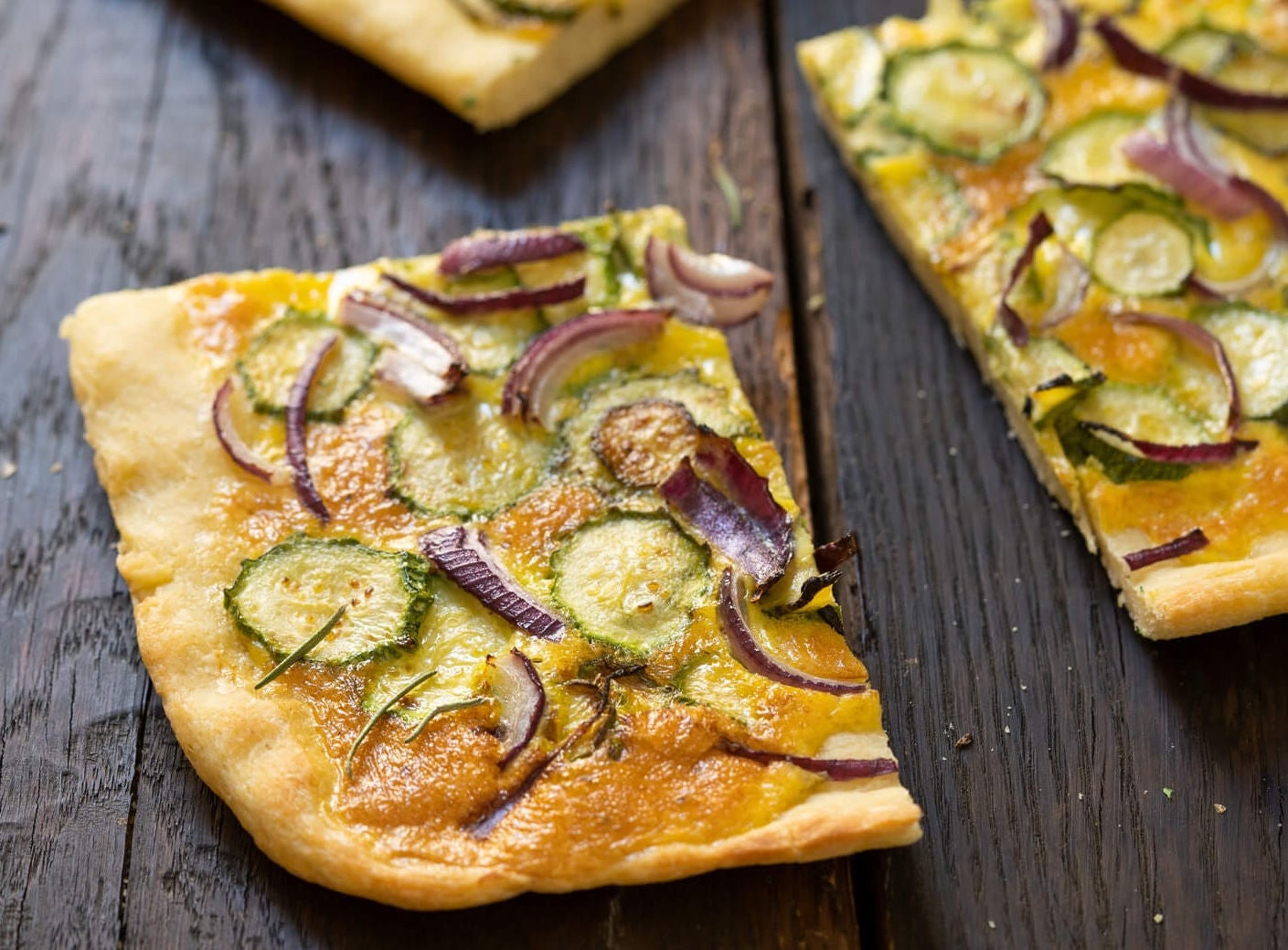 Slices of zucchini pizza on pita bread.