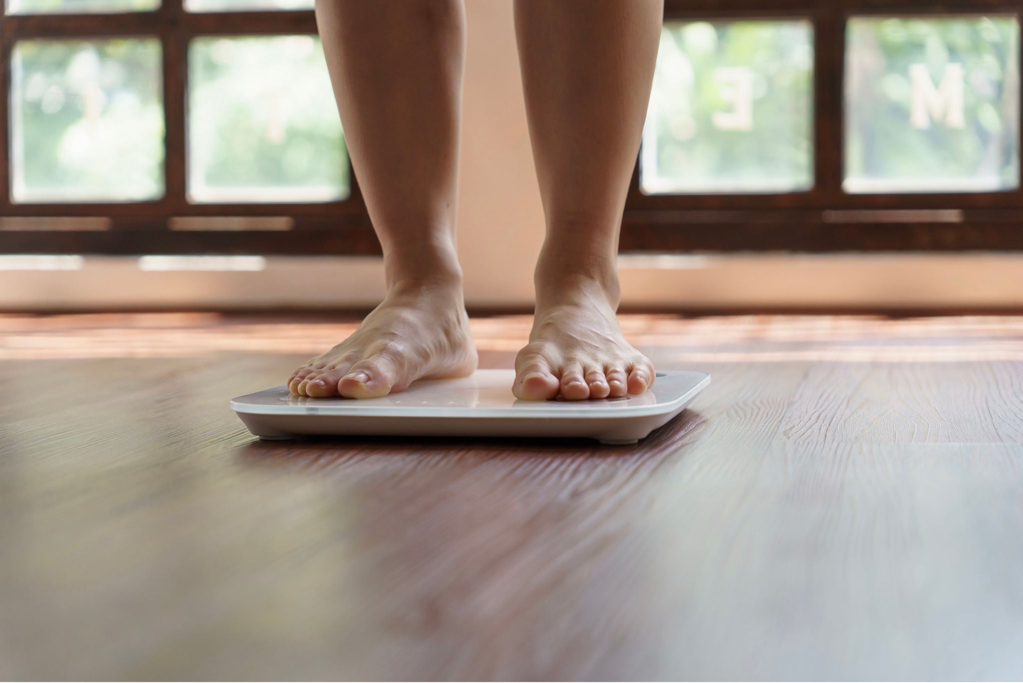 Person standing on a scale on a hardwood floor.