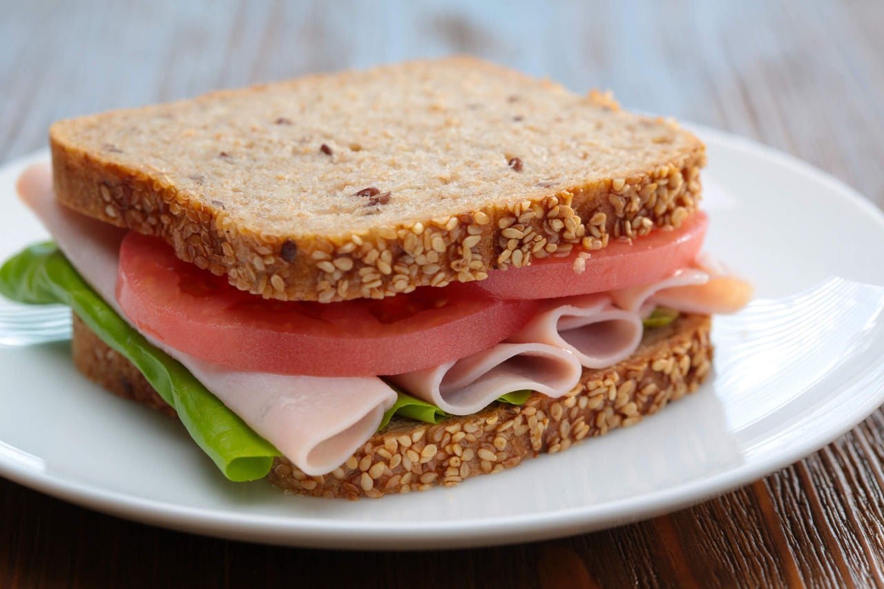 Turkey sandwich on whole grain bread with lettuce and tomatoes.