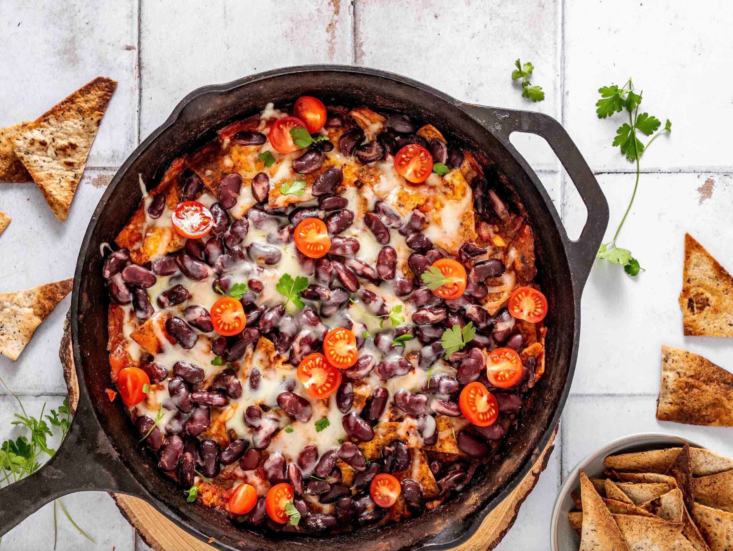 Skillet with black beans, ground beef, vegetables, tomatoes, chips and cheese.