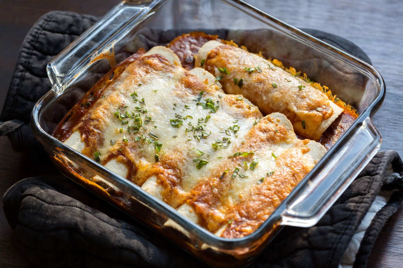Enchiladas with cheese on top in a glass casserole dish.