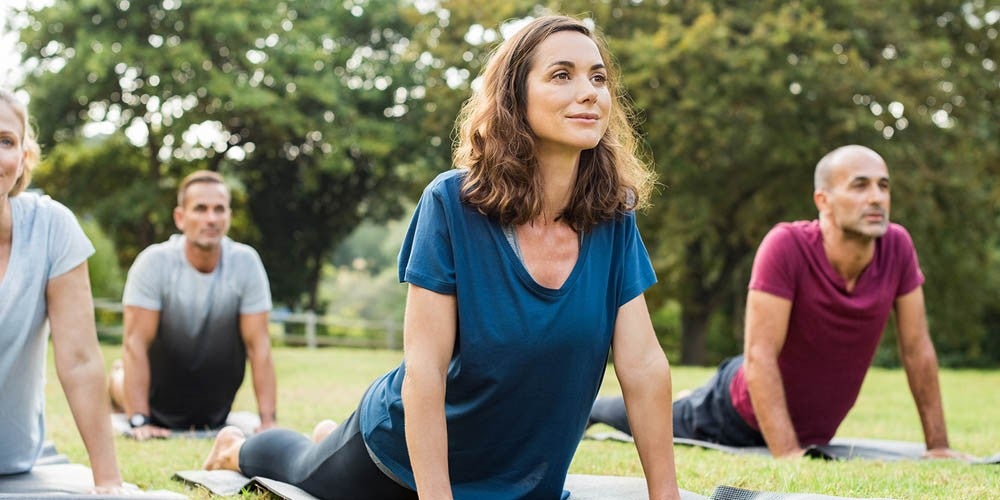 Grupo de personas practicando yoga al aire libre en un parque
