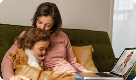  A mother and daughter sitting on a couch, talking virtually to a healthcare provider.