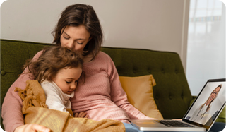  A mother and daughter sitting on a couch, talking virtually to a healthcare provider.