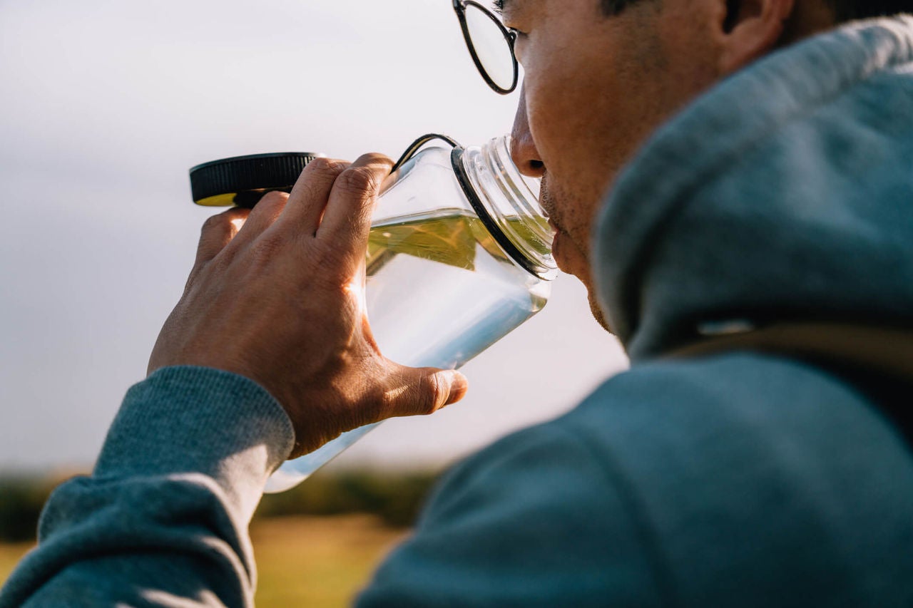 Man drinking from waterbottle outside.