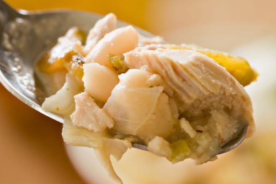 Close-up of a spoon with a bite of chicken white chili on it.