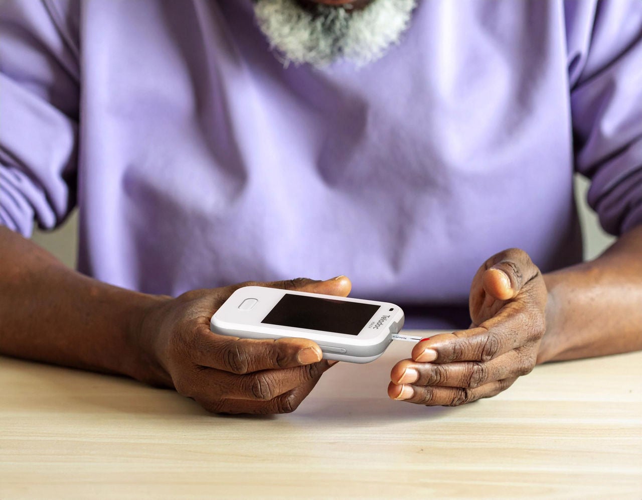 Man using a Teladoc blood glucose meter to check glucose levels.