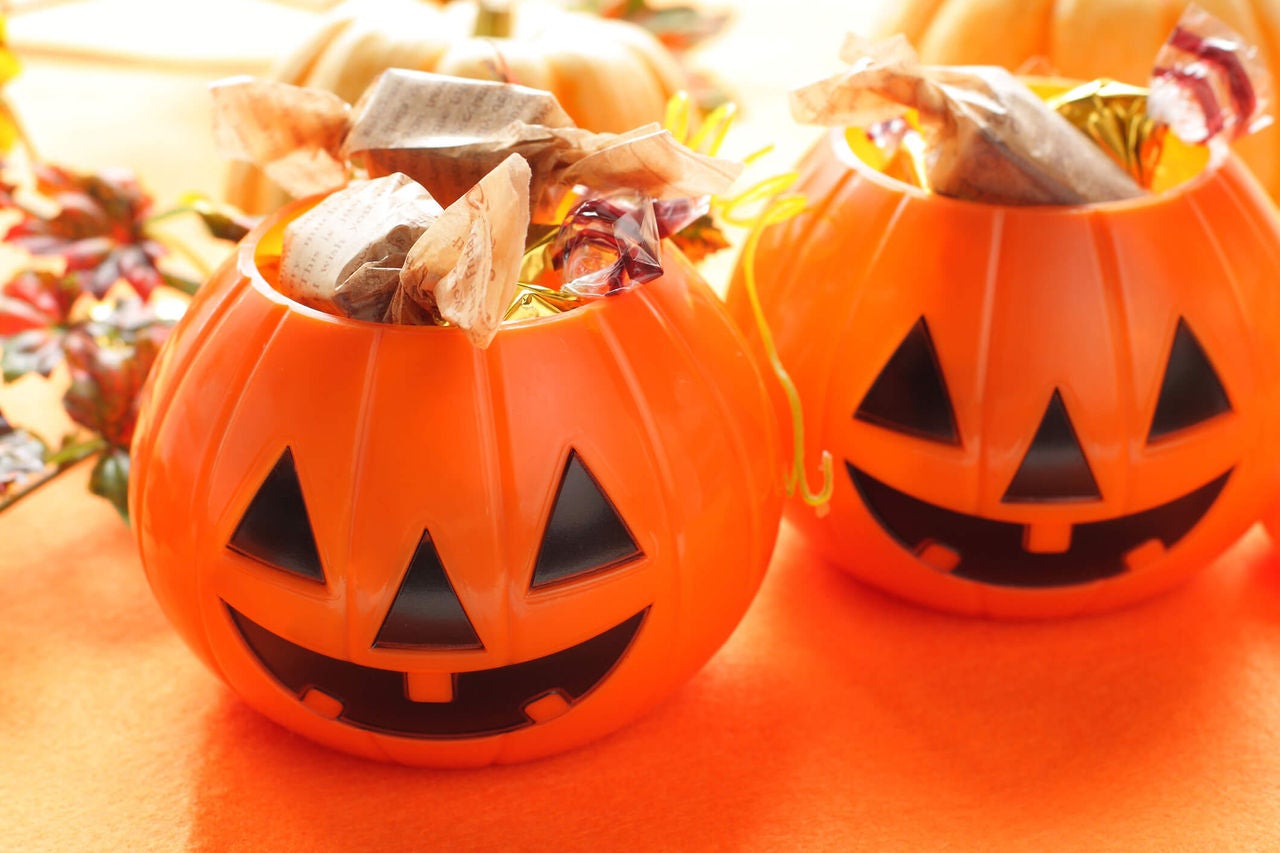 Two pumpkin shaped trick or treat baskets full of Halloween candy