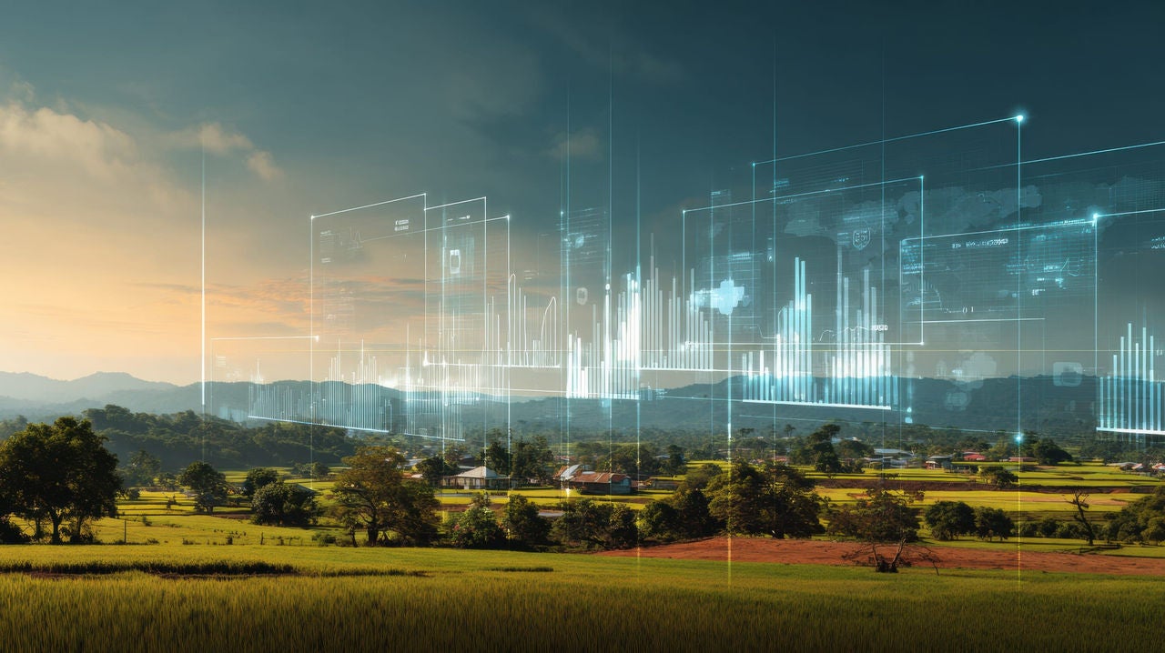Rural landscape at sunset with translucent digital data graphics overlaid across the sky.