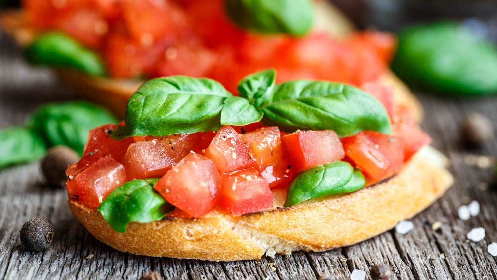 Fresh bruschetta topped with diced tomatoes and basil leaves on toasted bread.