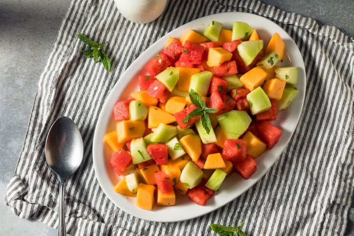 Bowl with cubed watermelon, melon, cantaloupe and small pieces of mint.