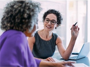 Two women in a professional setting have a conversation.