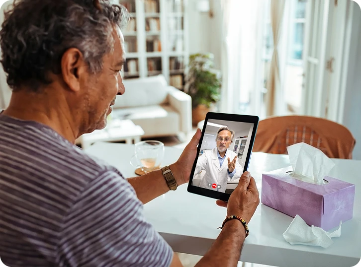  Man attending a virtual healthcare appointment on a tablet from home.