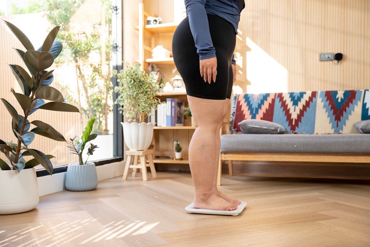 Bottom half of a woman standing on a scale in her living room