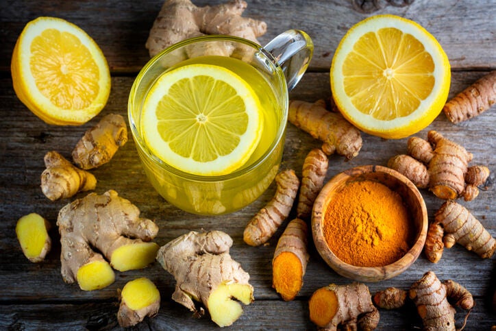 Overhead shot of a beverage surrounded by ginger, turmeric and lemon