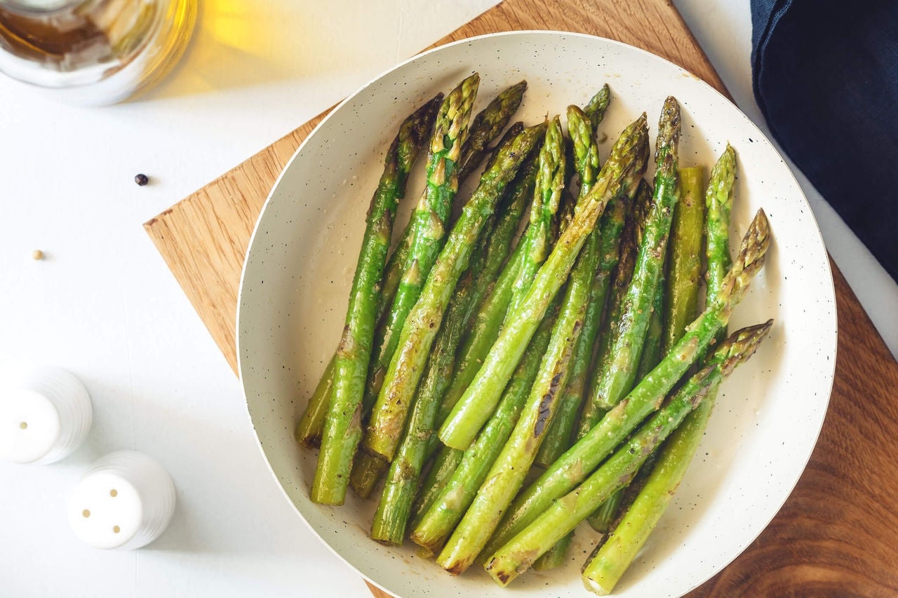 Cooked and seasoned asparagus spears on a plate.