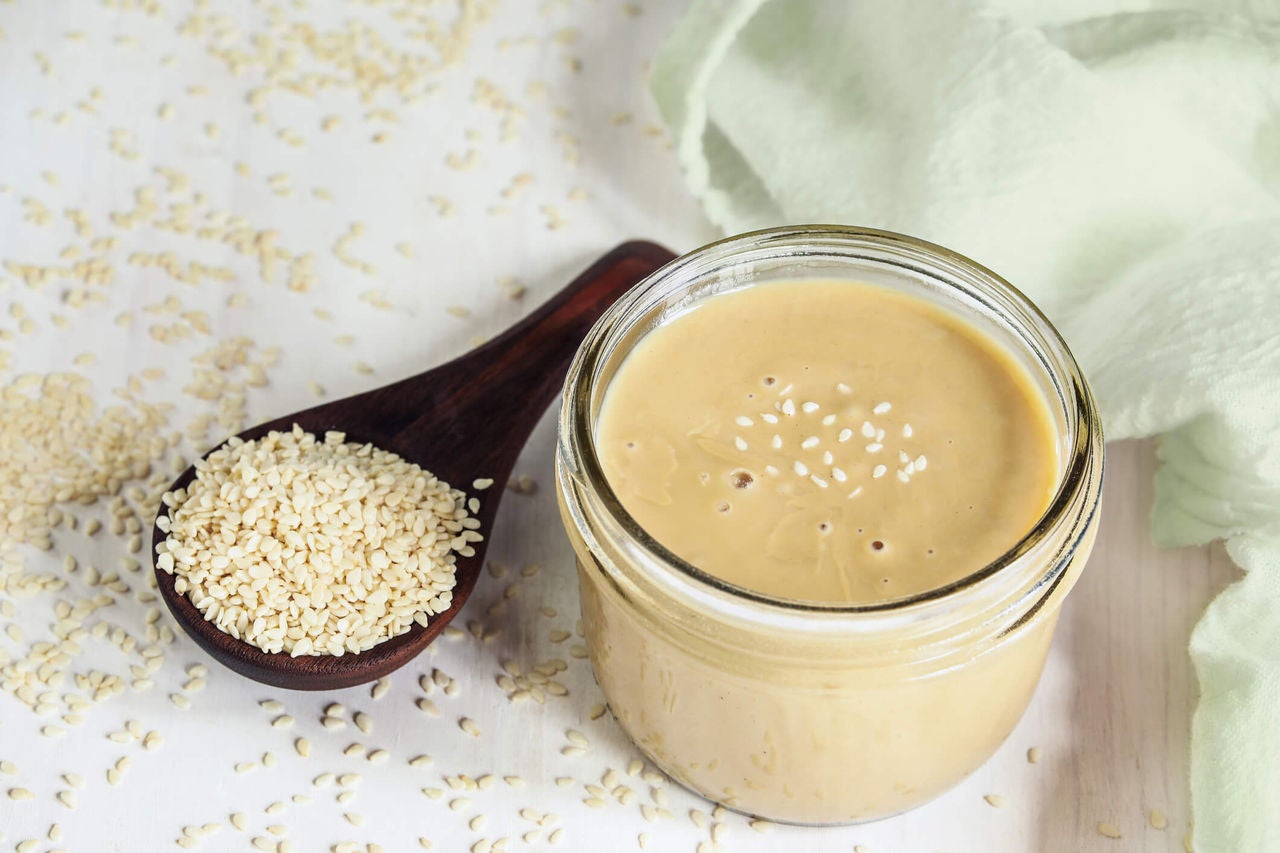 Brown dressing in a small glass jar topped with sesame seeds.