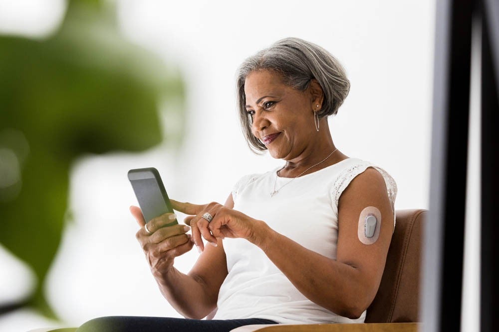 Mujer afroamericana mayor sonriente mientras realiza una videollamada con sus nietos.