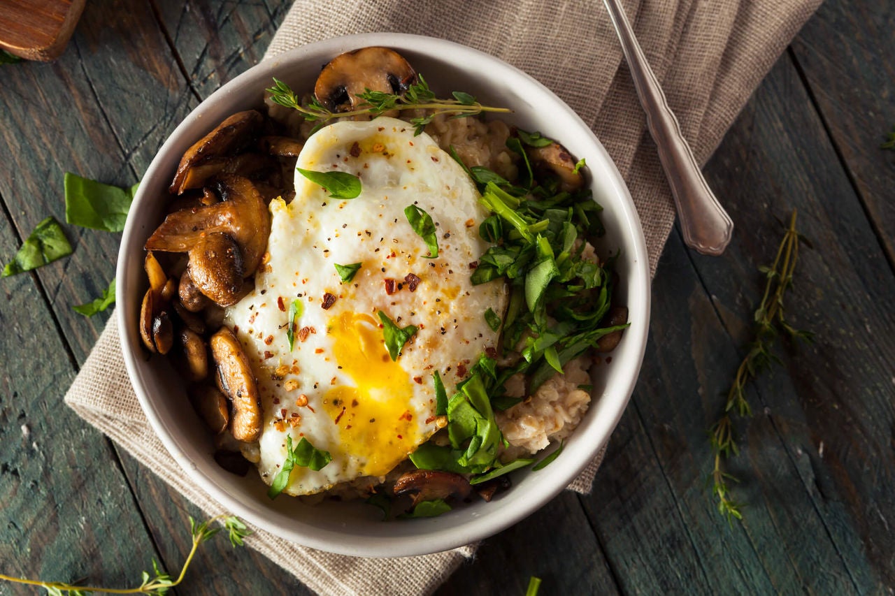 Bowl with barley, sliced mushrooms, chopped greens and a fried egg. 