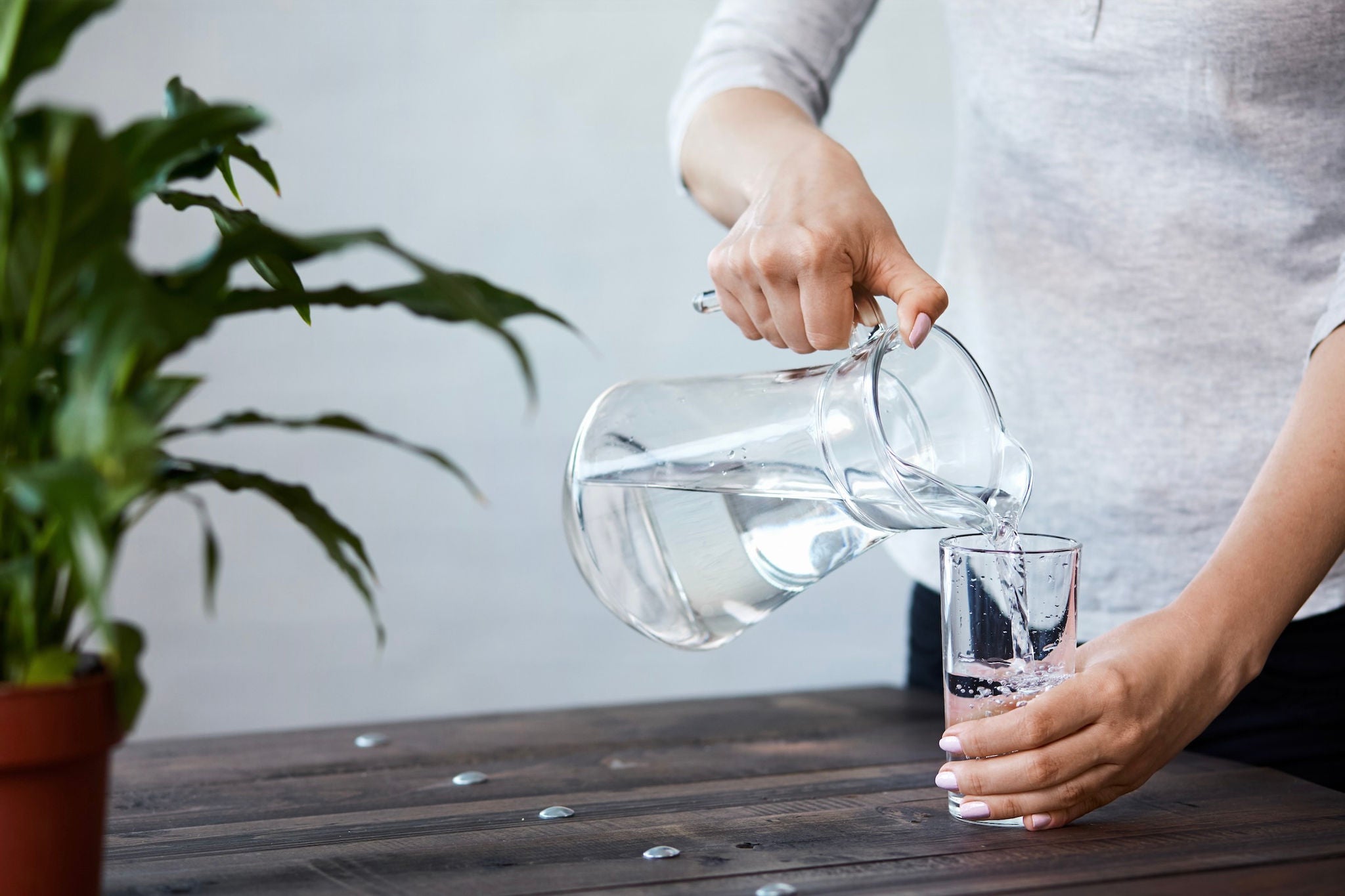 Person pouring water from a pitcher into a glass.