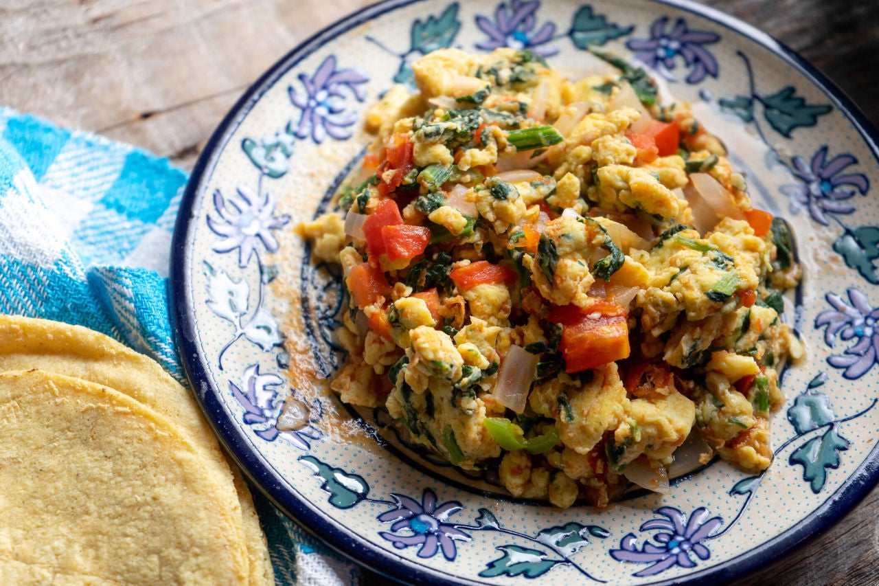 Egg scramble with onions, peppers and greens on a plate.