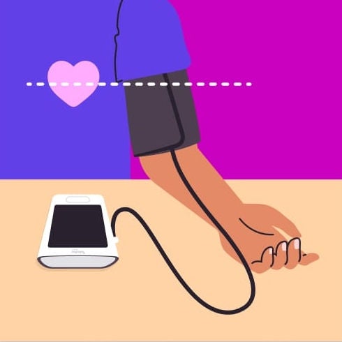Person wearing a blood pressure cuff on their upper arm with the monitor resting nearby.