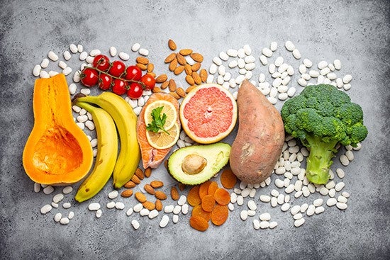 Vegetables, fruit and foods containing potassium over gray stone background, top view. Natural sources of potassium, vitamins and micronutrients for healthy balanced diet and avitaminosis prevention