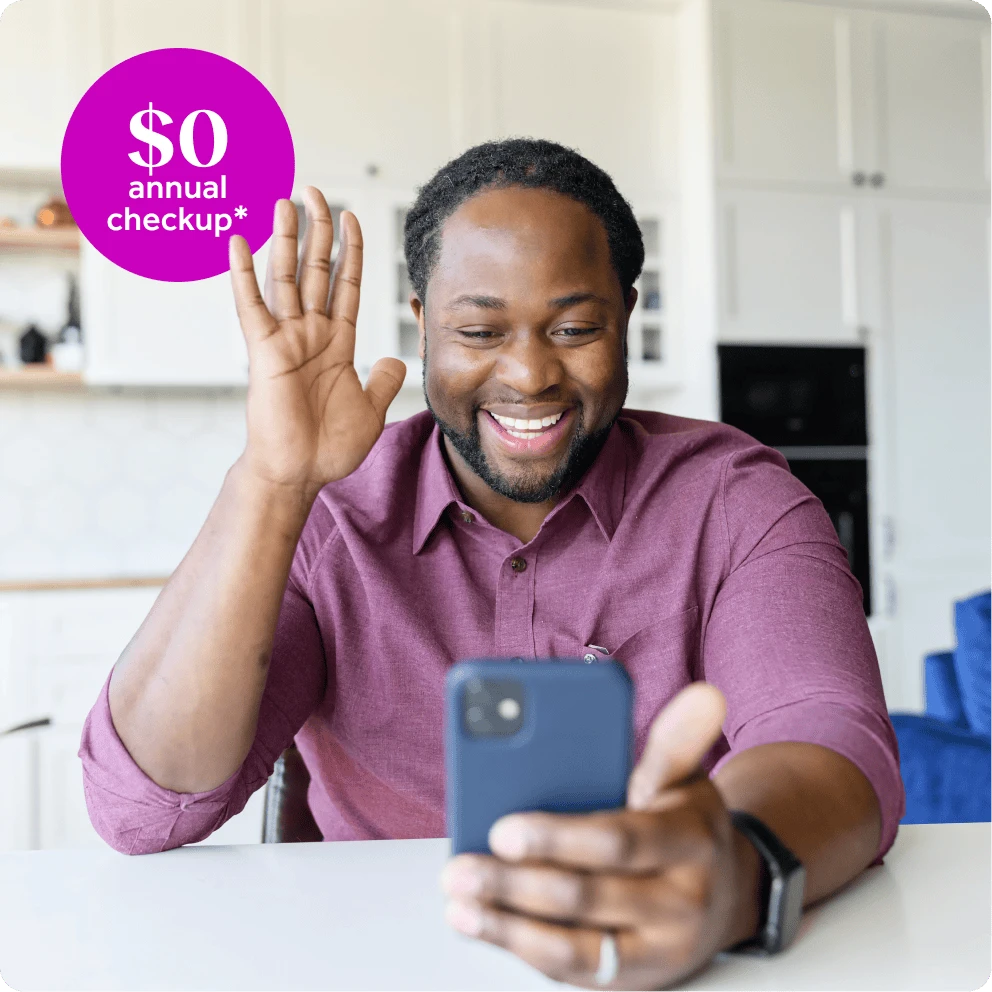 A man speaks to a healthcare provider using his phone while sitting in his home.