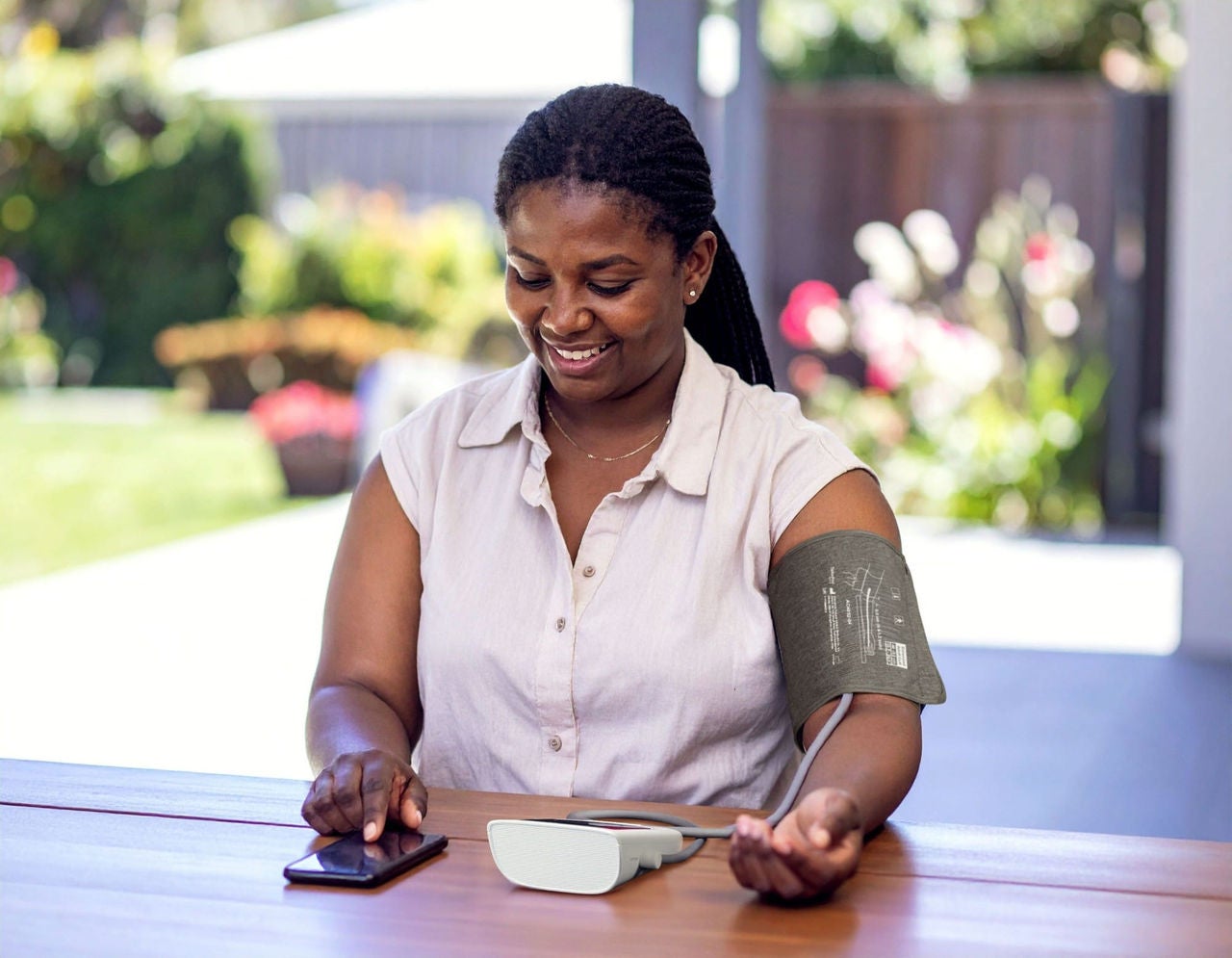 Woman sitting at a table taking her blood pressure