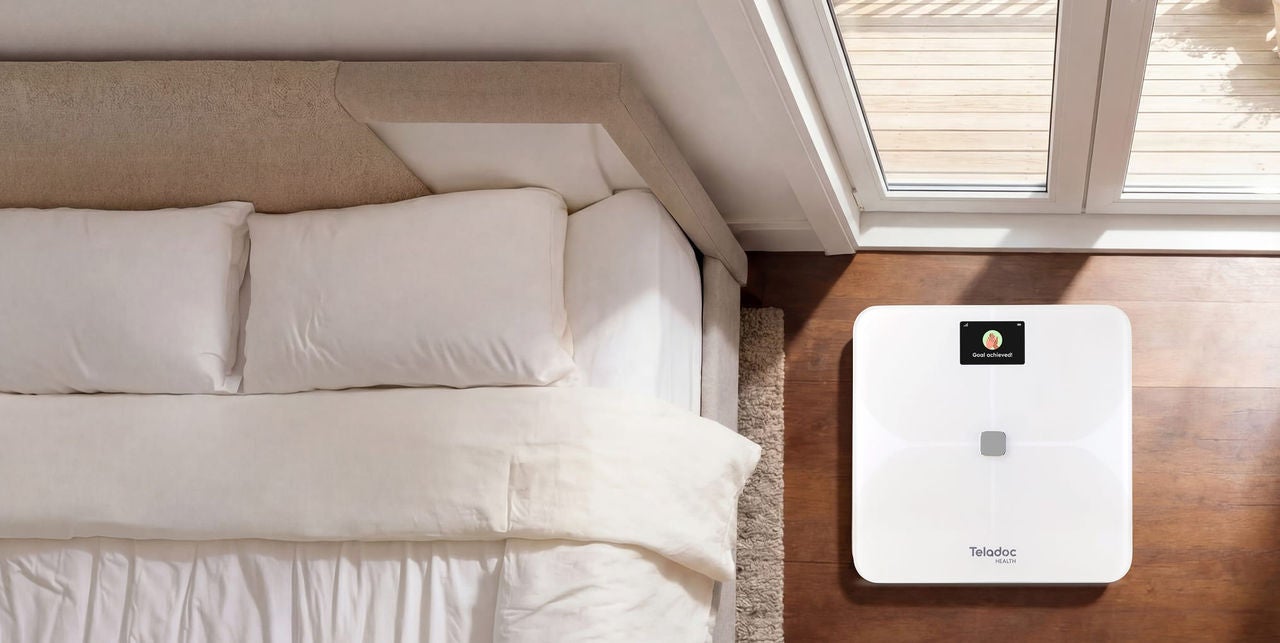 Room with an empty bed with a smart scale next to it on the floor