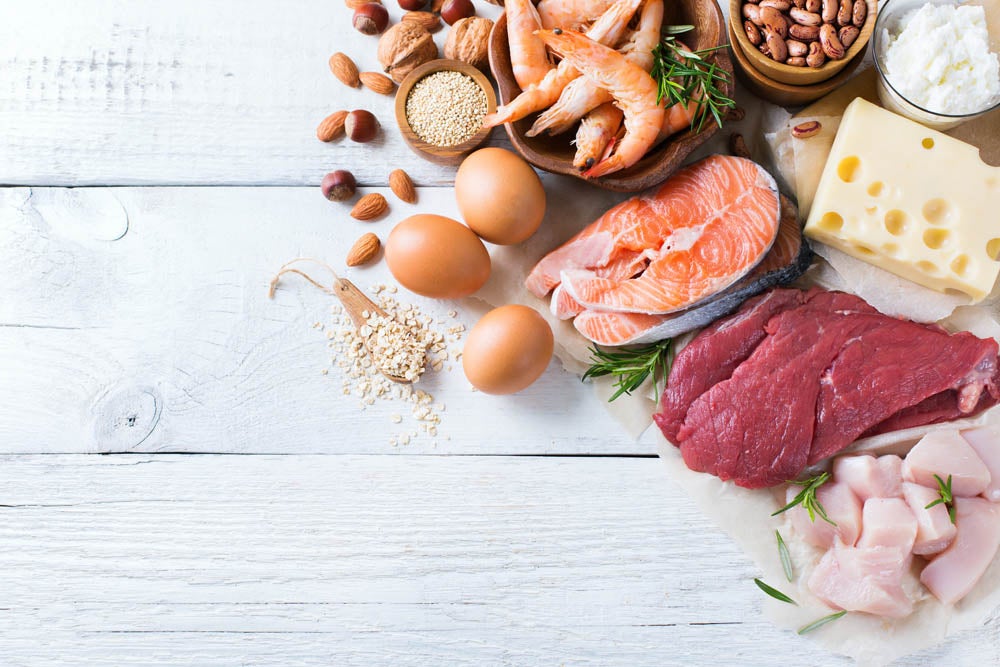 Assortment of healthy protein source and body building food. Meat beef salmon chicken eggs dairy products milk cheese yogurt beans quinoa nuts oat meal. Copy space background, top view flat lay