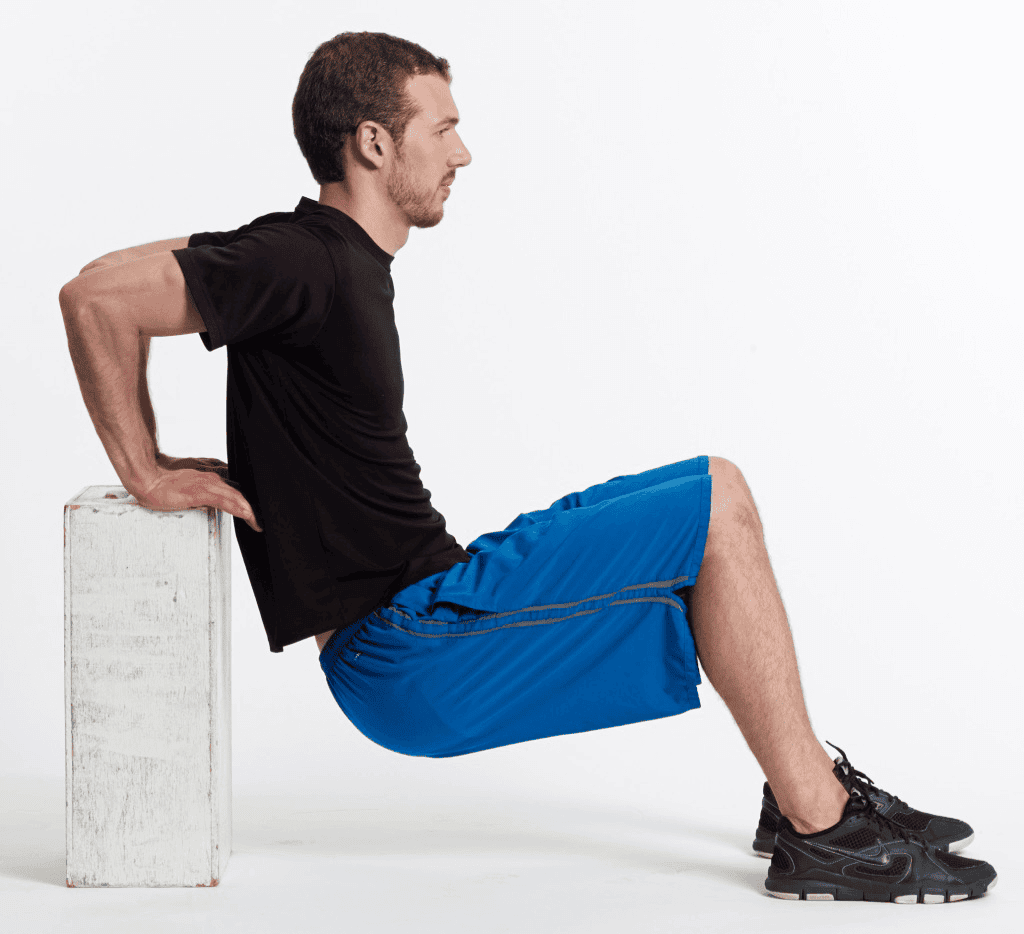 Hombre haciendo fondos de tríceps usando un banco blanco