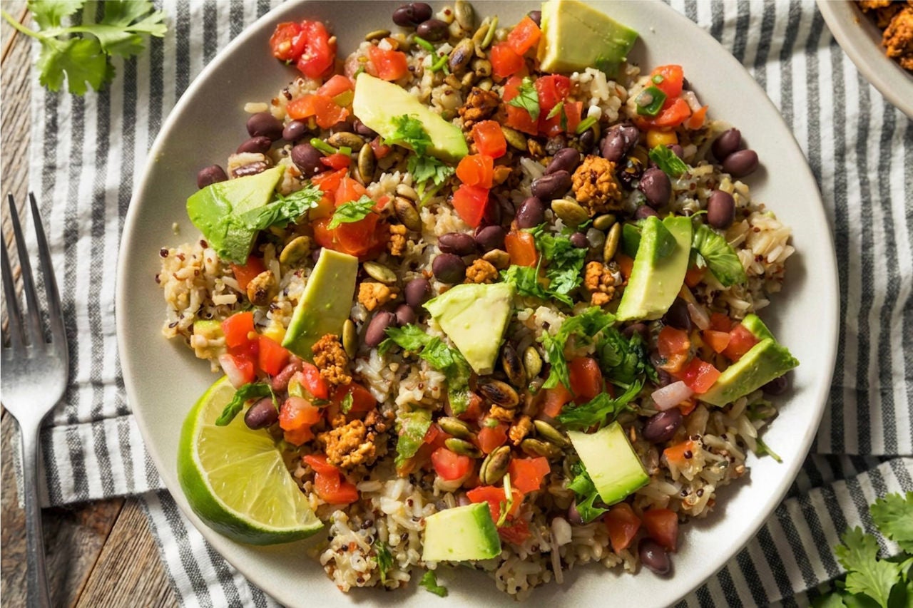 Bowl with chopped vegetables, avocado, rice, quinoa and tofu sofritas crumbles. 