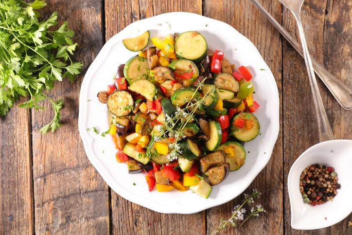Plate with chopped vegetables forming a ratatouille with a herb garnish.