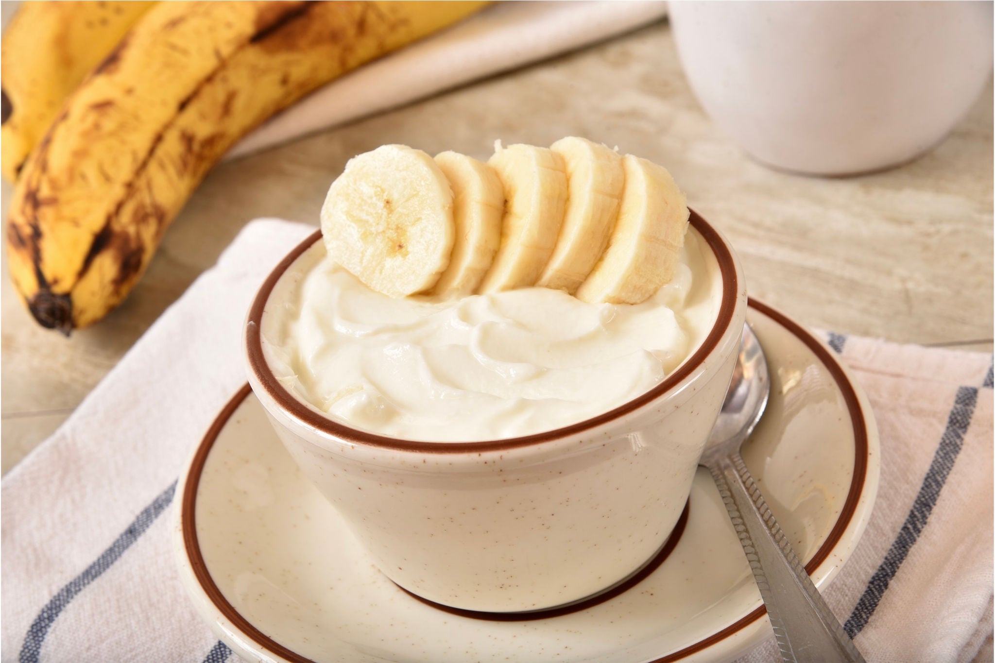 Bowl of plain yogurt topped with banana slices.