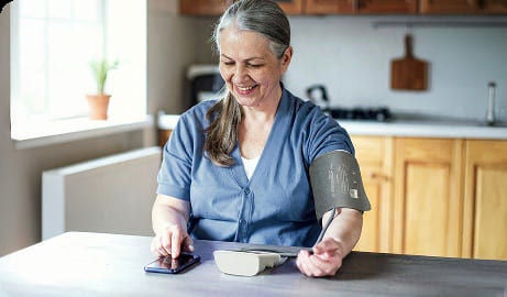  A woman uses a medical device to take her blood pressure reading.