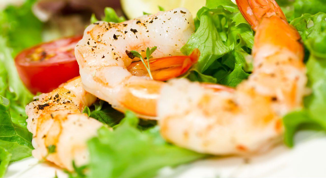 Close-up of shrimp with lettuce and a piece of tomato in the background.