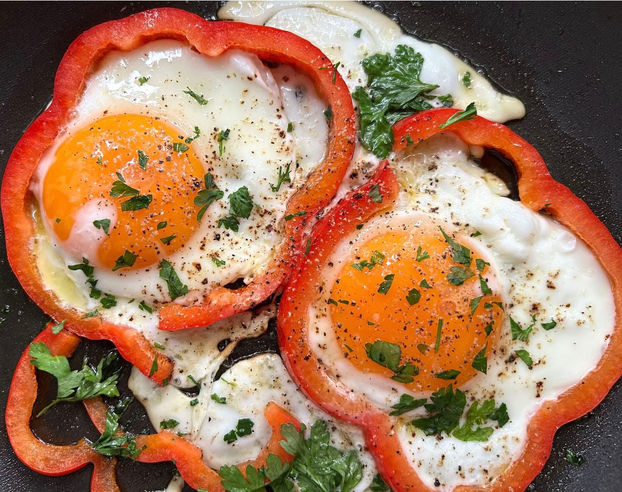 Pan with fried eggs in bell pepper rings.