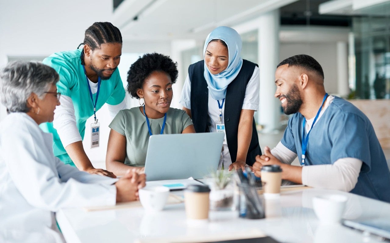 Health care providers at a table looking at a laptop screen together