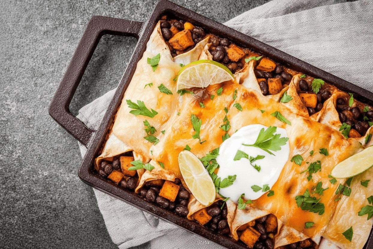 Pan with enchiladas filled with black beans and sweet potato, topped with greek yogurt, cilantro and lime wedges.