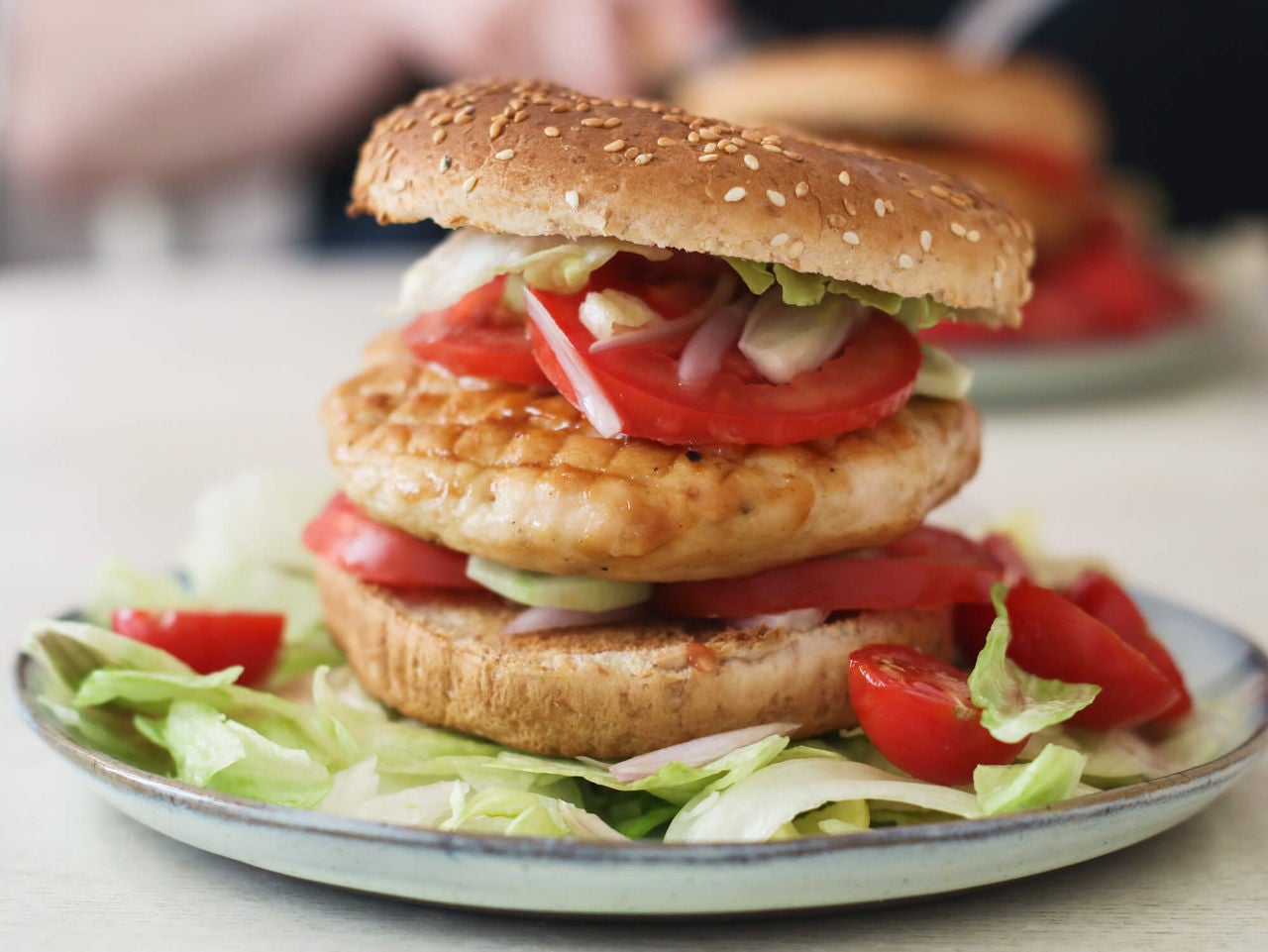 Grilled chicken breast on a whole wheat bun with tomatoes and lettuce.