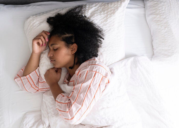 Woman sleeping in bed in a well-lit room.