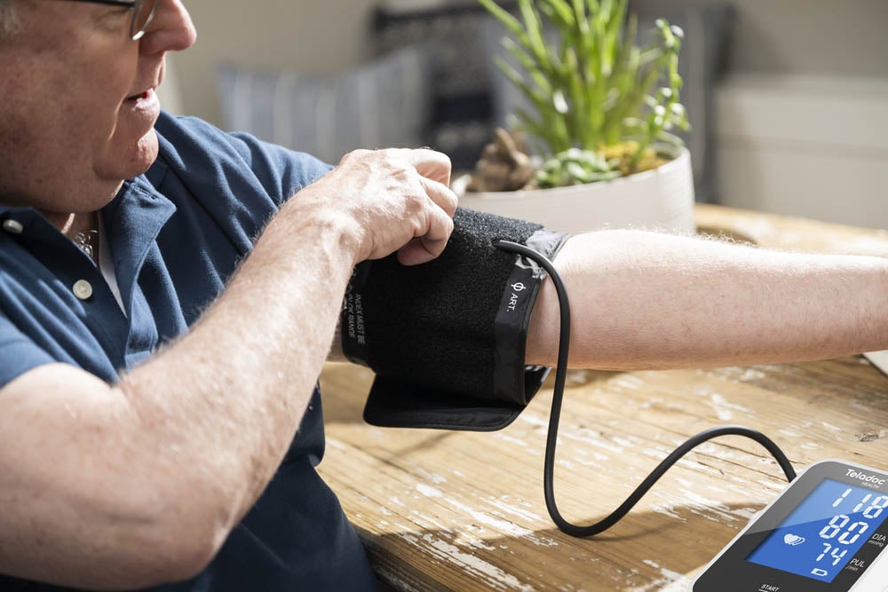 A man putting a blood pressure cuff on his arm.