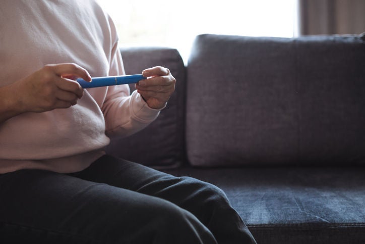 Closeup of person sitting on couch holding GLP-1 medication
